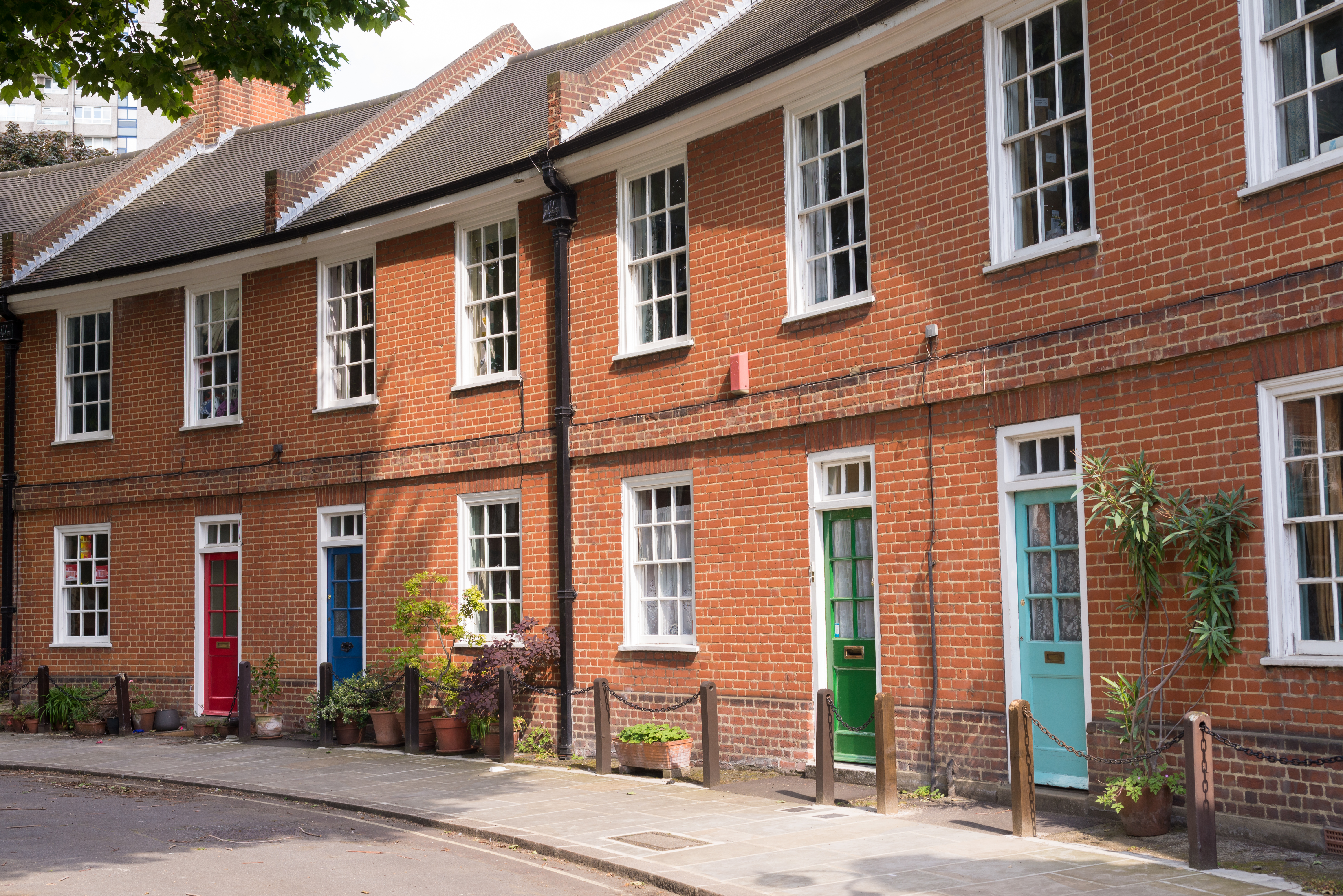 Restored Victorian red brick houses with colored doors on a local road in London, UK